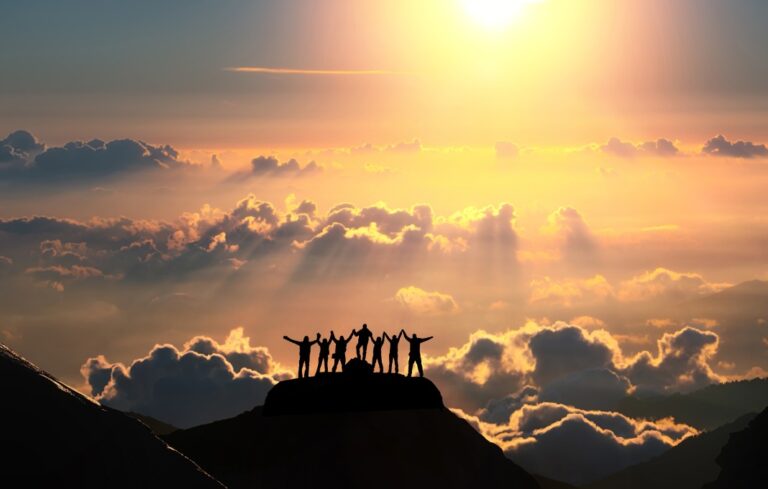 A group of people stands on a hill over the beautiful cloudscape.