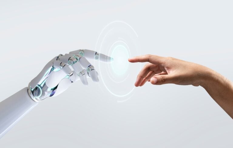 Human hand reaching out to robot hand on white background