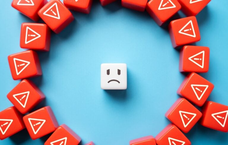 Sad face cube surrounded by red cubes with danger signs on them.