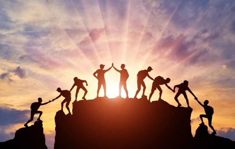 Silhouette of climbers who climbed to the top of the mountain thanks to mutual assistance and teamwork