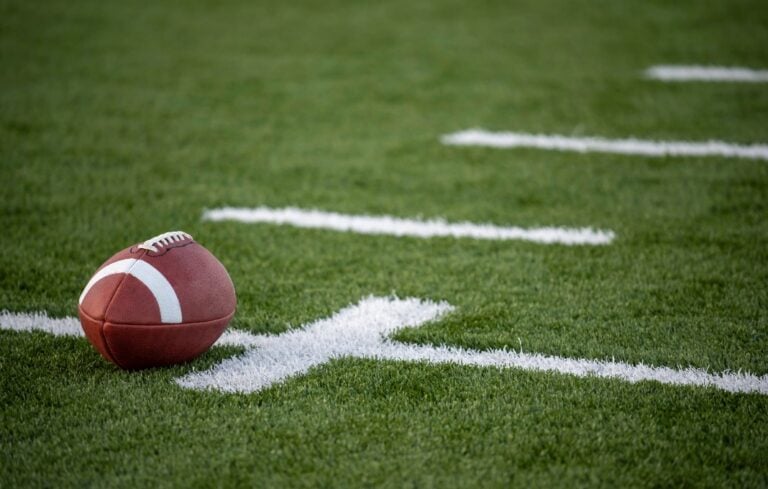 A brown leather american football on a green playing field