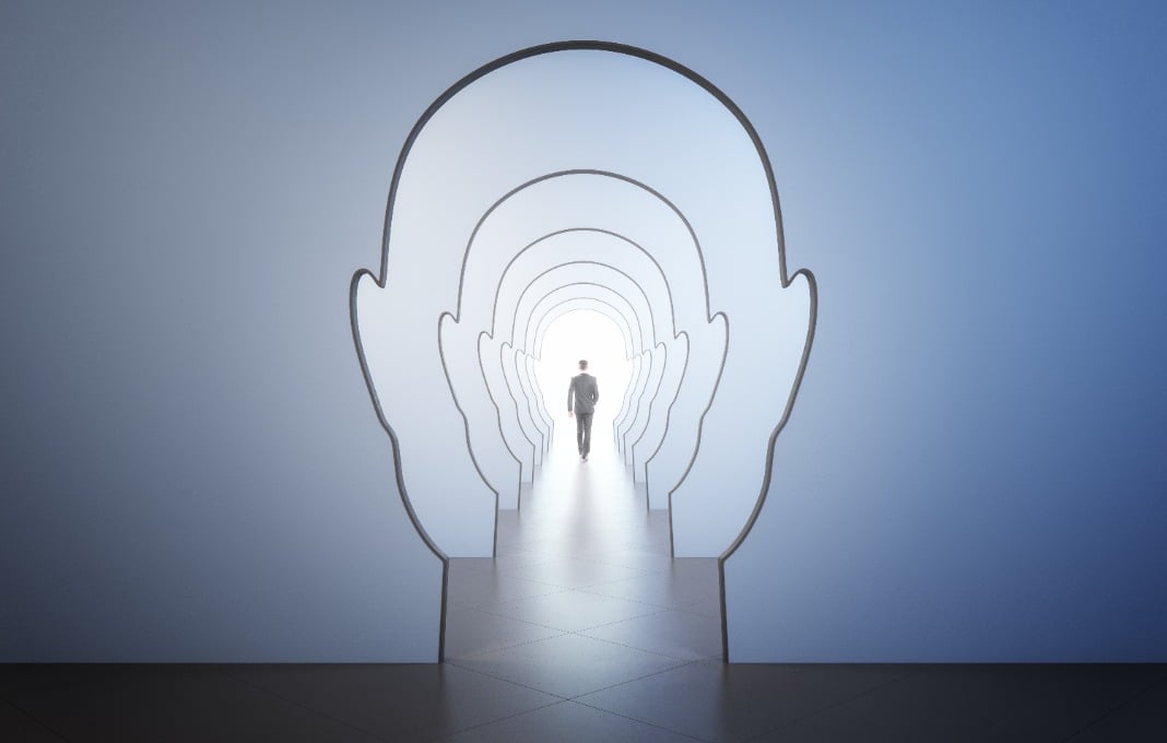 walking man back leading to light spot in the end of corridor through walls in form of human heads