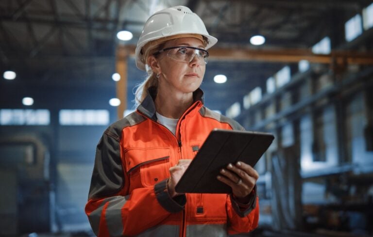 Professional Heavy Industry Engineer/Worker Wearing Safety Uniform and Hard Hat Uses Tablet Computer.