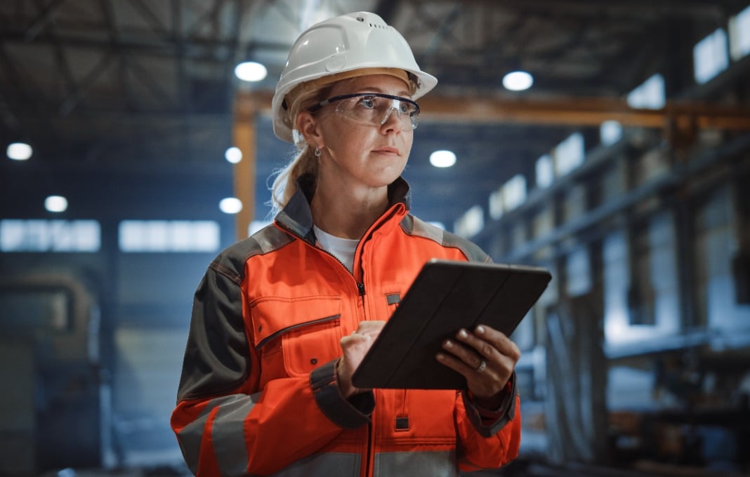 Professional Heavy Industry Engineer/Worker Wearing Safety Uniform and Hard Hat Uses Tablet Computer.