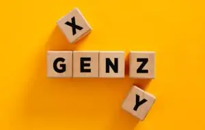 Wooden cubes composing the acronym gen z with generation x and y aside on yellow background