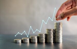 Hand stacking coins on black wooden table with profit line chart growth up.