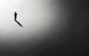 Silhouette of man walking in the night toward the light, view from above