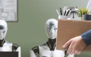 Person carrying cardboard box of belongings past line of robots