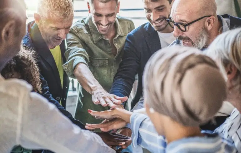 Diverse business team stacks hands in unity, showcasing teamwork and partnership in a dynamic workplace.