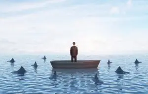 Businessman standing in a boat surrounded by sharks