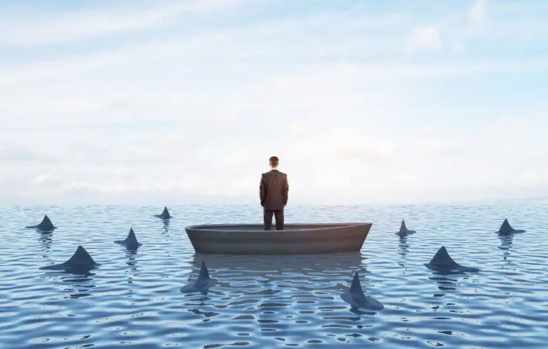 Businessman standing in a boat surrounded by sharks