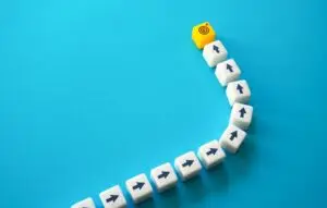 Line of cubes with arrows pointing towards cube with bullseye on blue background