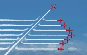 One plane cutting through the trails of a line of other planes flying through the sky