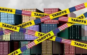 Caution tape printed tariffs in front of shipping containers