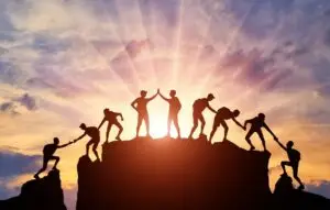 Silhouette of climbers who climbed to the top of the mountain thanks to mutual assistance and teamwork