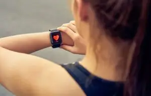 Young woman checking the sports watch measuring heart rate and performance after running.