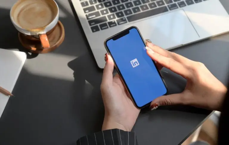 holding iPhone with LinkedIn screen.