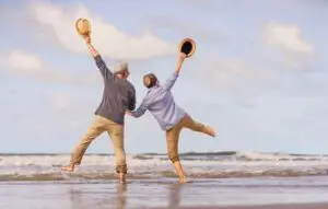 senior couple jumping on the beach