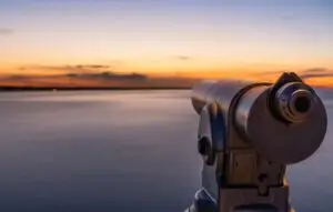 A telescope on a lookout at a beautiful sunset and a long exposure of the water on the sea.