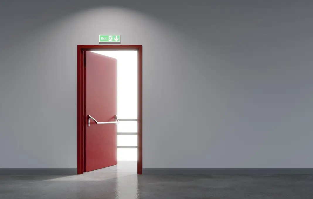 Fire exit red metal door in white sapce building
