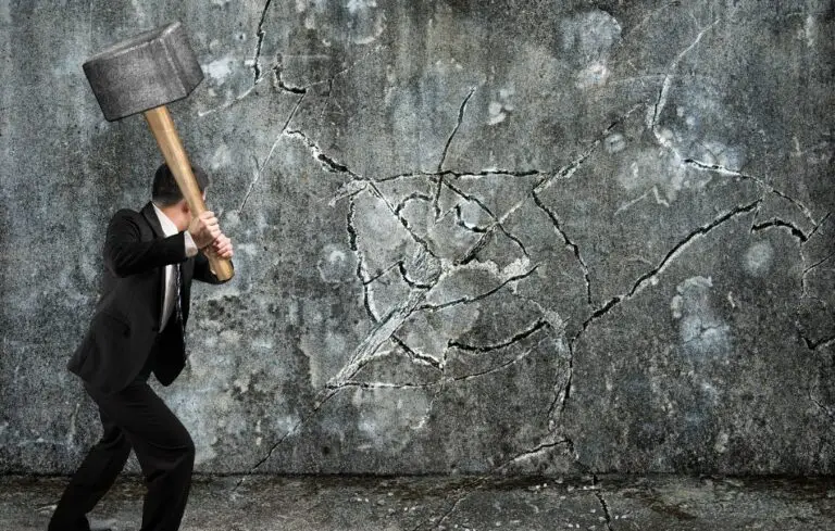 businessman using sledgehammer cracking wall broken on concrete