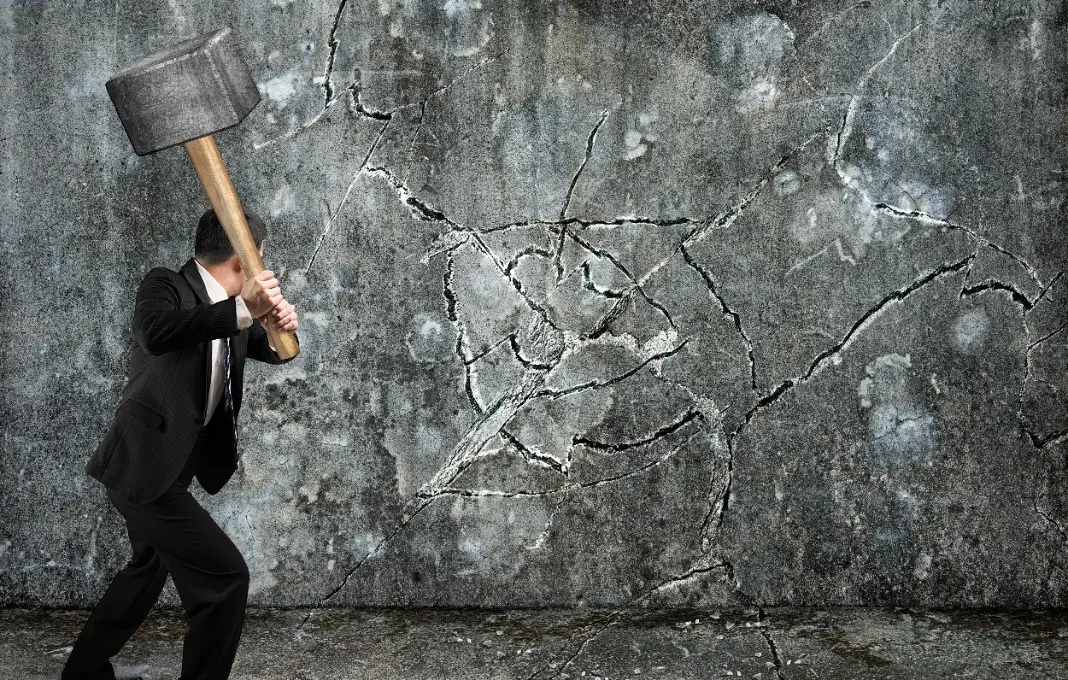 businessman using sledgehammer cracking wall broken on concrete