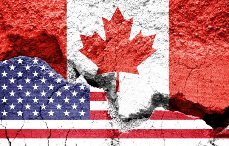 US American and Canadian flags on cracked background.