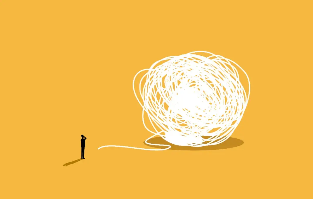 Businessman looking at big tangled ball of string
