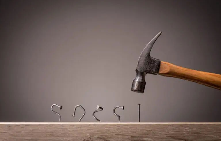 Line of bent nails and a hammer above an unbent one