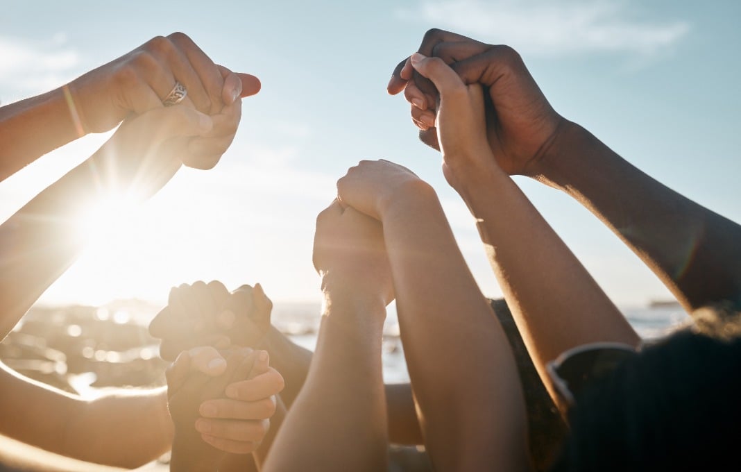 Group of people holding hands on the beach