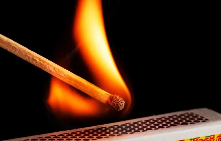 A matchstick lights after it is struck agains the flint surface of a match box.