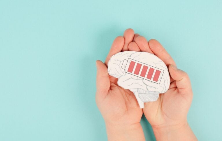 Hands holding a paper cutout of a brain with a battery symbol on it