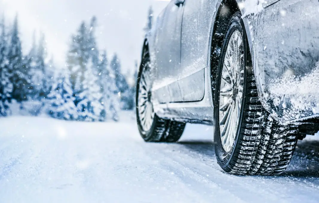 Winter tire. Car tire on snow road. Tires on snowy road detail.