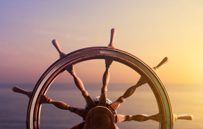 Ship steering wheel with the ocean at sunset in the background. 3D Rendering