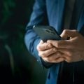 Businessman in suit with mobile phone in hands. Man typing message, using social net. Checking news. Making business meeting. Modern office.General manager,ceo.Calling to partner.Planning working day.